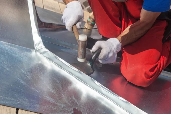 Roofer builder worker finishing folding a metal sheet using rubber mallet. — Stock Photo, Image