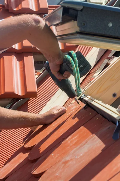 Roofer instala un tragaluz en el nuevo techo con un taladro . — Foto de Stock