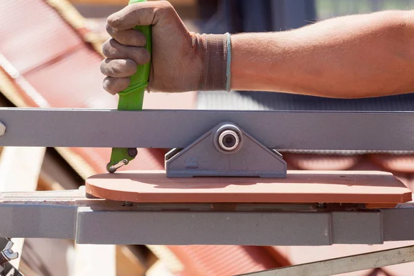 Roofer constructor trabajador utilizar el cortador de azulejos para crear un tamaño correcto de baldosas de cerámica roja natural . — Foto de Stock