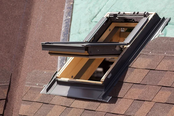 Closeup del tragaluz de la ventana en un techo con tejas de asfalto o