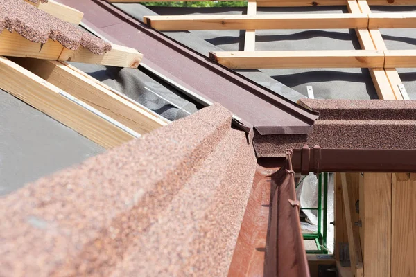 Neues Asphaltschindeldach mit brauner Regenrinne, Holzbalken und Dampfschutzschicht. — Stockfoto