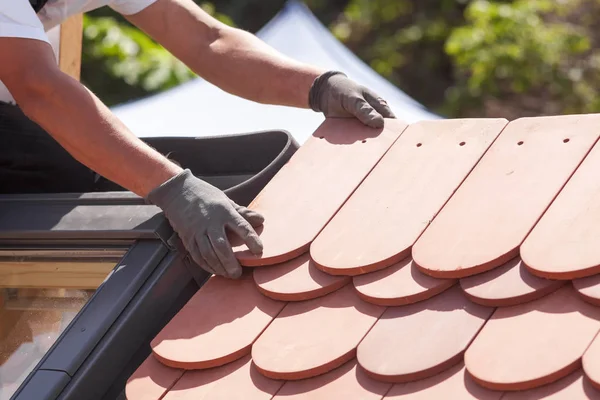 Manos de tejado colocando baldosas en el techo. Instalación de azulejos rojos naturales — Foto de Stock