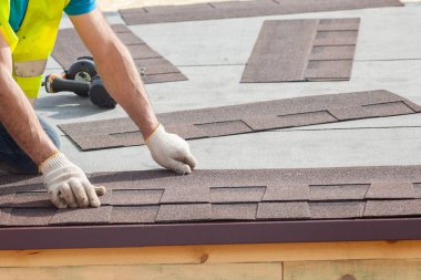 Asfalt çatı (Zona) üzerinde yeni bir çerçeve ev koyarak inşaat işçisi.
