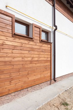 Yeni kahverengi bakır oluk içinde beyaz duvar ve ahşap plakalar ile ev.