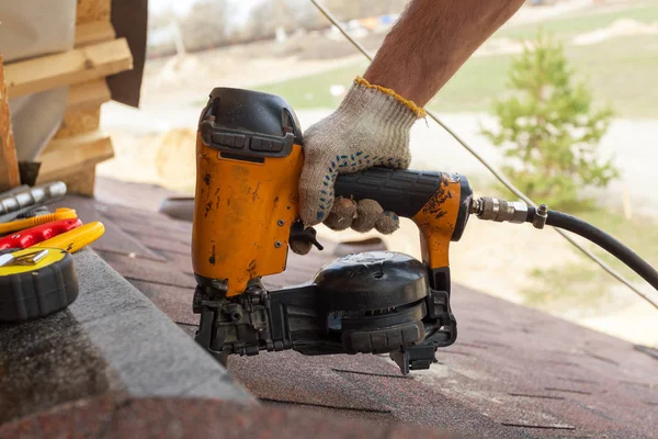 Construction worker putting the asphalt roofing (shingles) with nail gun on a large commercial apartment building development. — Stock Photo, Image