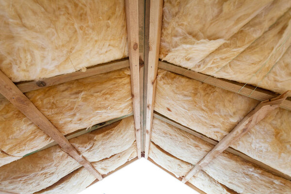 Iinsulation of attic with fiberglass cold barrier and insulation material.