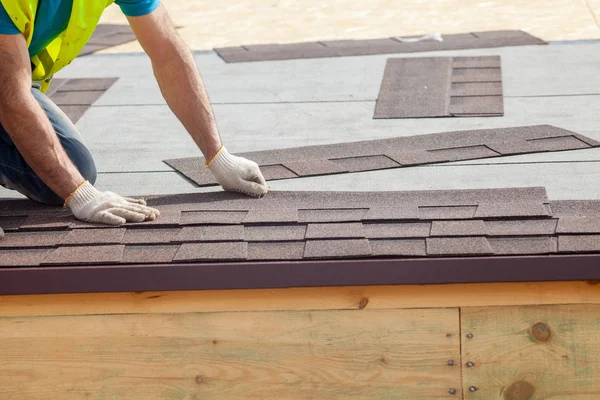 Construction worker putting the asphalt roofing (shingles) on a new frame house — Stock Photo, Image