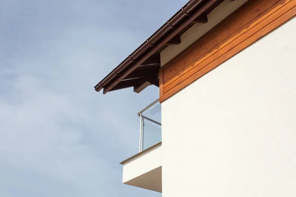 Nueva casa con canalón de lluvia marrón, pared blanca y balcón . — Foto de Stock