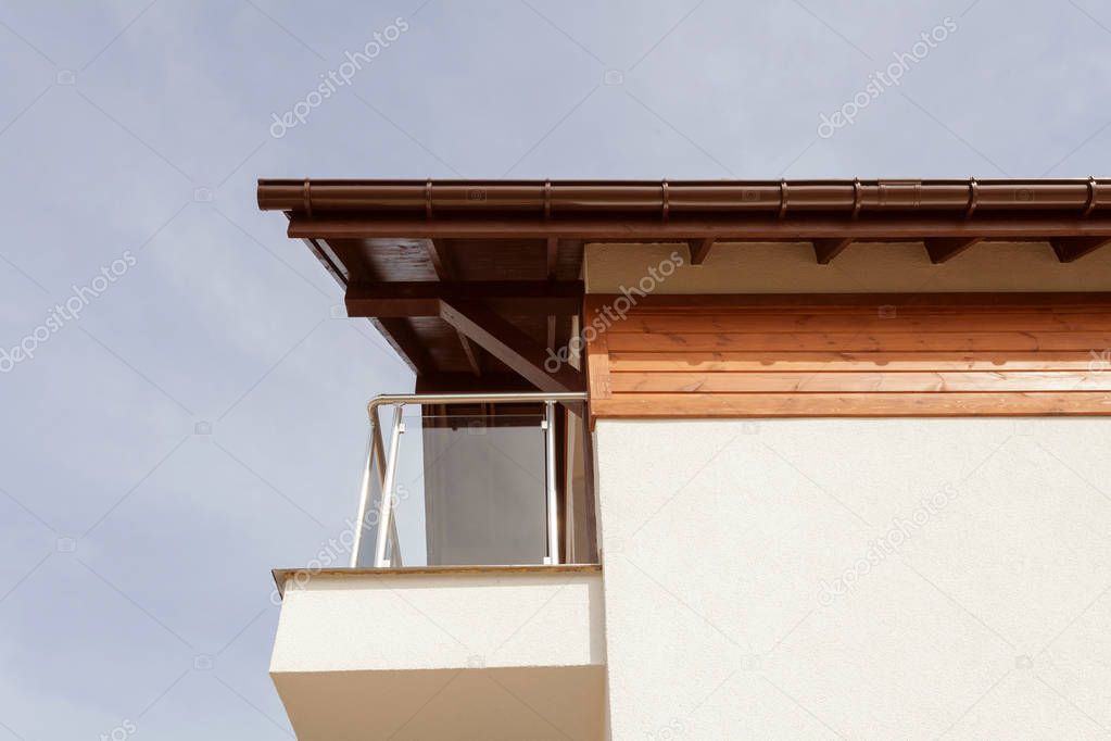 New house with brown rain gutter, white wall and balcony.