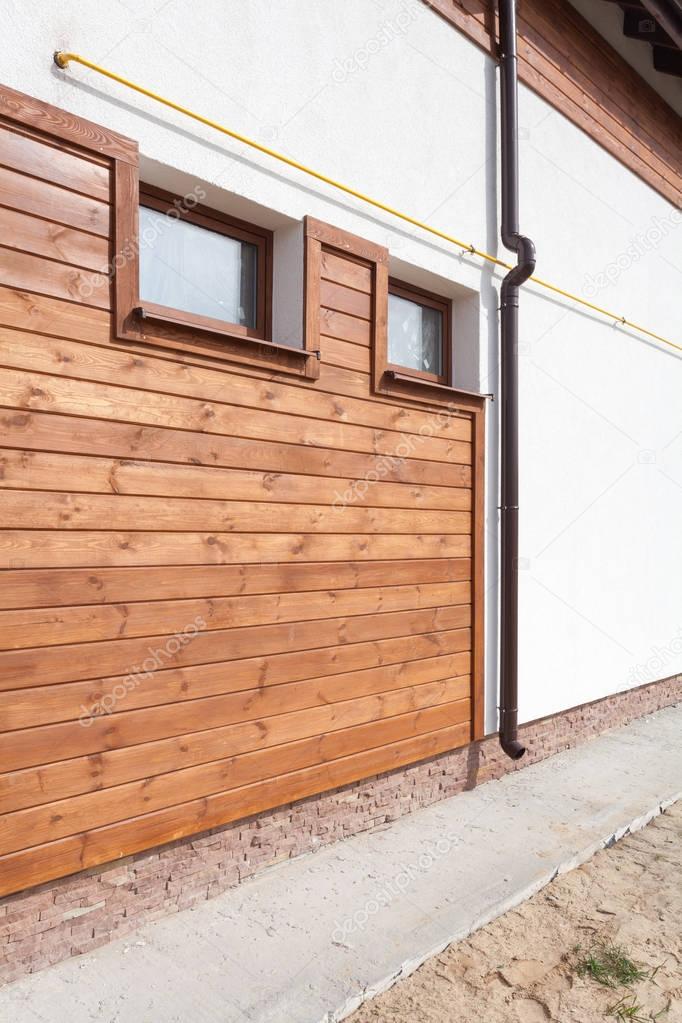 New brown copper gutter in house with white wall and wooden planks.