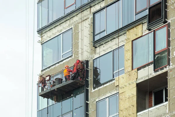 Inspeccionando el sitio de construcción grande. Trabajadores de la construcción de nueva casa, instalar ventanas, aislamiento de la pared, balcón. Construcción de edificios industriales — Foto de Stock