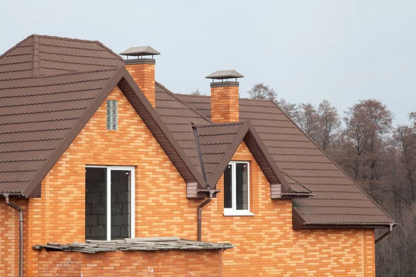 Nouvelle maison en brique avec cheminée modulaire, tuile métallique revêtue de pierre, fenêtres en plastique et gouttière . — Photo