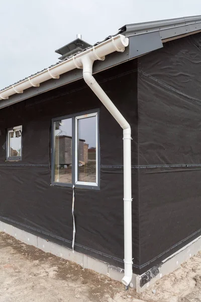 SIP panel house construction. New gray metal tile roof with white rain gutter.