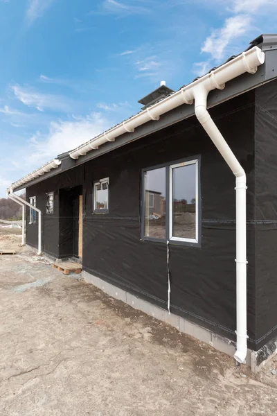 Casa del panel SIP con nuevo techo de baldosas de metal gris, canalón de lluvia blanca y aislamiento . — Foto de Stock