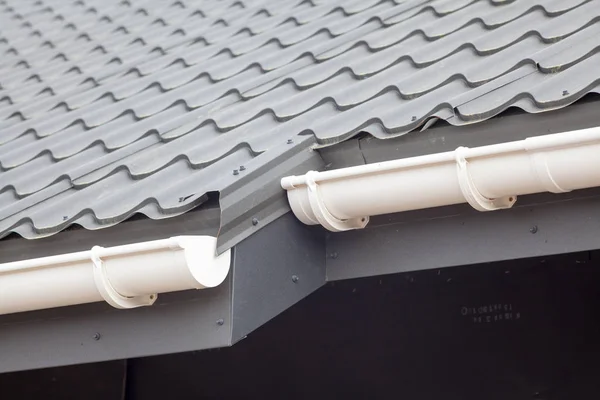 New gray metal tile roof with white rain gutter.