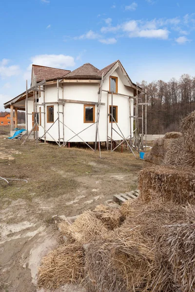 Construcción de casa de adobe con techo de paja y ventanas de plástico  . — Foto de Stock