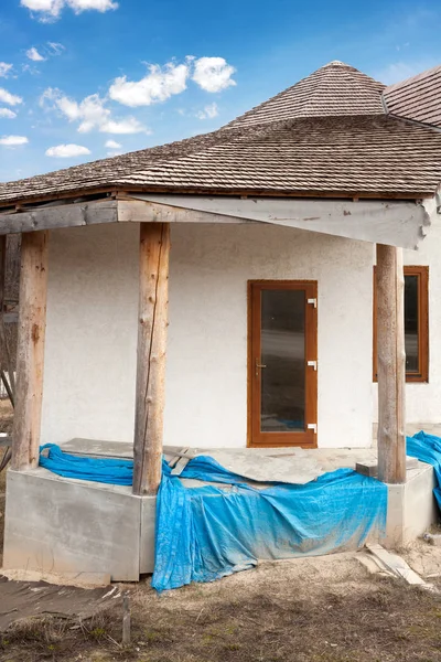 Construcción de casa de adobe con techo de paja y ventanas de plástico  . — Foto de Stock