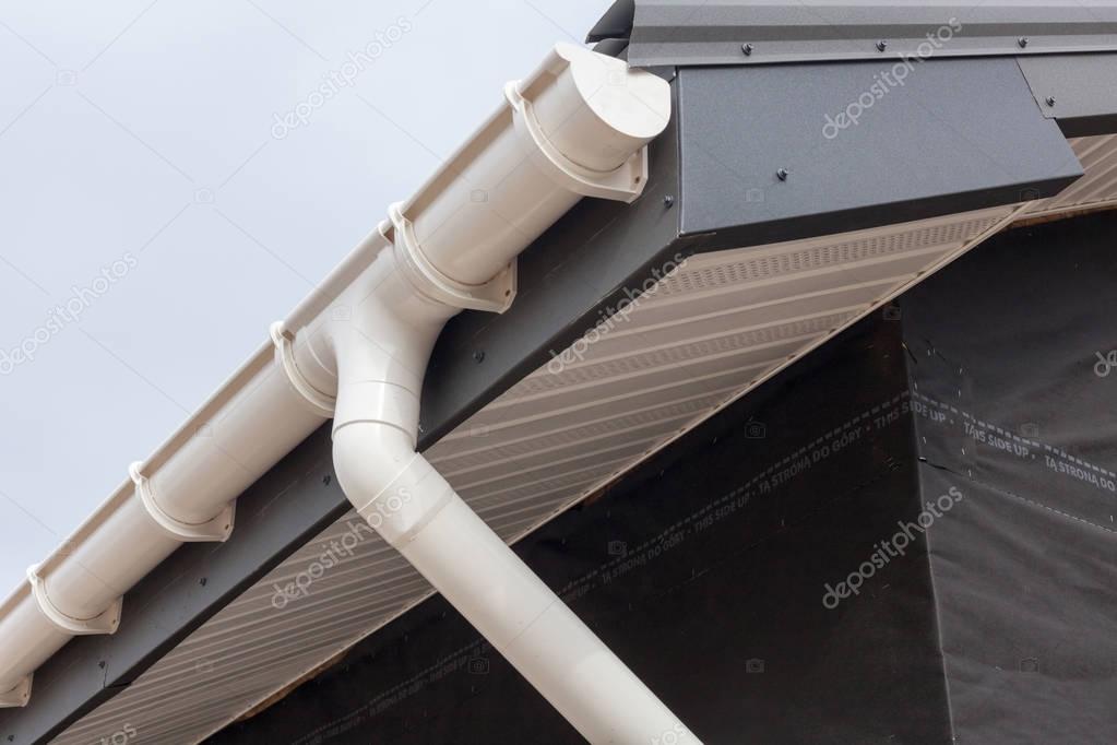 SIP panel house construction. New gray metal tile roof with white rain gutter.