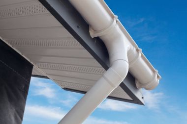 Panel ev yapımı yudumlayın. Yeni beyaz yağmur oluk. Plastik dış cephe kaplaması Soffits ve saçak mavi gökyüzü ile drenaj sistemi.