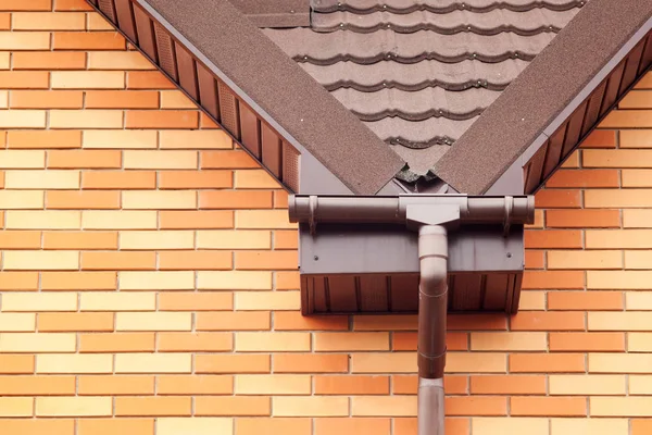 New white rain gutter on a roof with  Drainage System, Stone Coated Metal tile, Plastic Siding Soffits and Eaves. — Stock Photo, Image