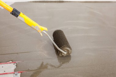 Elektrikli yerden ısıtma sistemi yüklemesi yeni evde. İşçi çimento ile silindir hizalama.