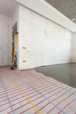 Elektrikli yerden ısıtma sistemi yüklemesi yeni evde. Beton ve kırmızı elektrik telleri closeup.