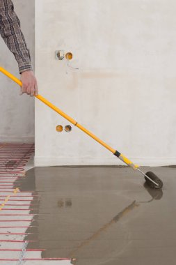 Elektrikli yerden ısıtma sistemi yüklemesi yeni evde. Silindir dökme beton zemin için