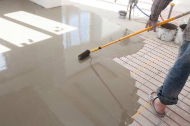 Elektrikli yerden ısıtma sistemi yüklemesi yeni evde. Silindir dökme beton zemin için