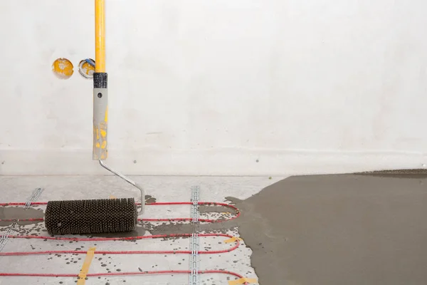 Elektrikli yerden ısıtma sistemi yüklemesi yeni evde. Rooler için closeup hizalamak beton. — Stok fotoğraf