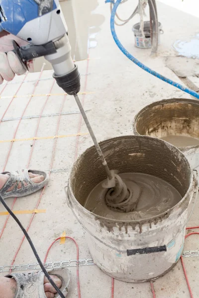 Elektrikli yerden ısıtma sistemi yüklemesi yeni evde. İşçi çimento hazırlamak için beton el mikseri kullanın. — Stok fotoğraf