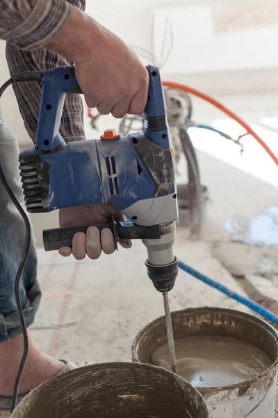 Elektrikli yerden ısıtma sistemi yüklemesi yeni evde. İşçi çimento hazırlamak için beton el mikseri kullanın.