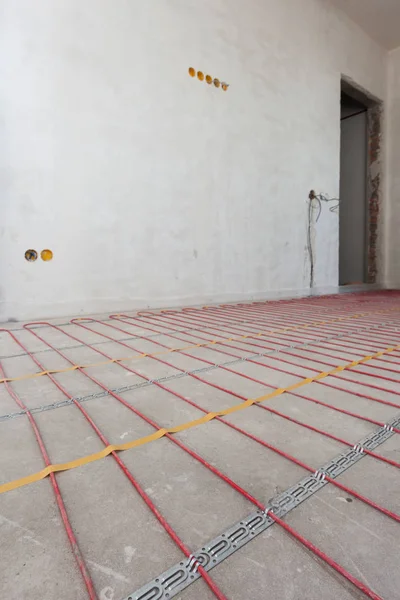 Sistem pemanas lantai listrik instalasi di rumah baru. Penutupan beton dan kabel listrik merah . — Stok Foto