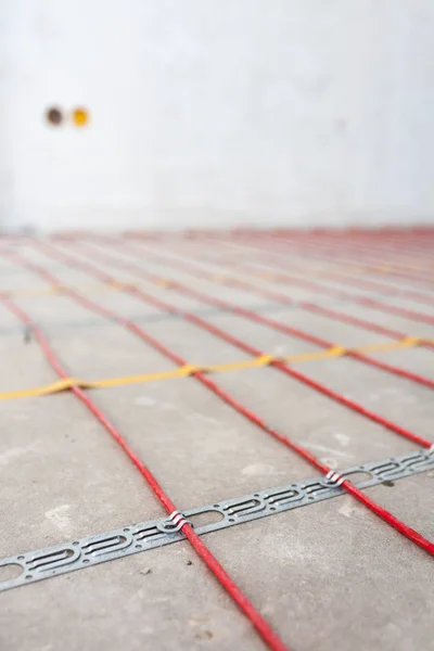 Electric floor heating system installation in new house. Closeup of  red electrical wires.