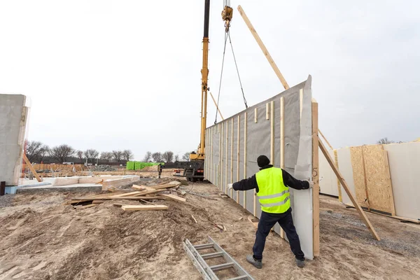 Працівники будівельників з краном встановлюють структурні ізольовані панелі SIP. Будівництво нового каркасного енергоефективного будинку — стокове фото