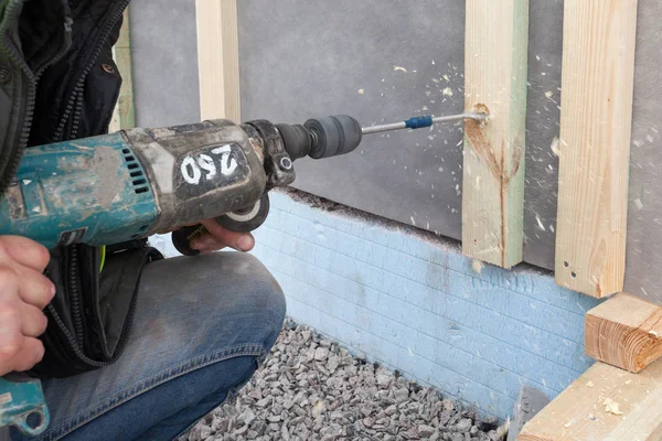 Arbeiter verwenden Bohrer, um ein Loch in strukturell isolierte Platte zu machen — Stockfoto