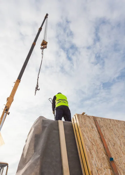 Costruttore di tetti con gru che installa pannelli isolanti strutturali SIP. Costruire nuova casa ad alta efficienza energetica telaio — Foto Stock