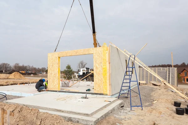 Працівники будівельників з краном встановлюють структурні ізольовані панелі SIP. Будівництво нового каркасного енергоефективного будинку . — стокове фото