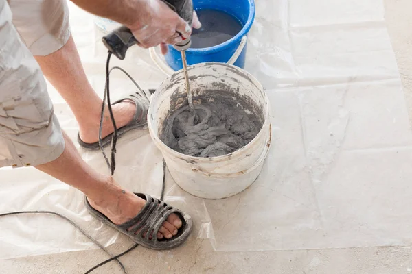 Elektrikli yerden ısıtma sistemi yüklemesi yeni evde. İşçi çimento hazırlamak için beton el mikseri kullanın. — Stok fotoğraf