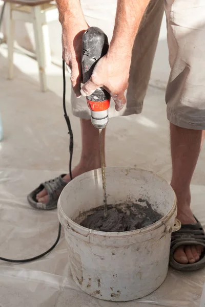Elektrisk golvvärme systeminstallation i nya hus. Arbetstagaren använder konkreta hand mixer för att förbereda cement. — Stockfoto