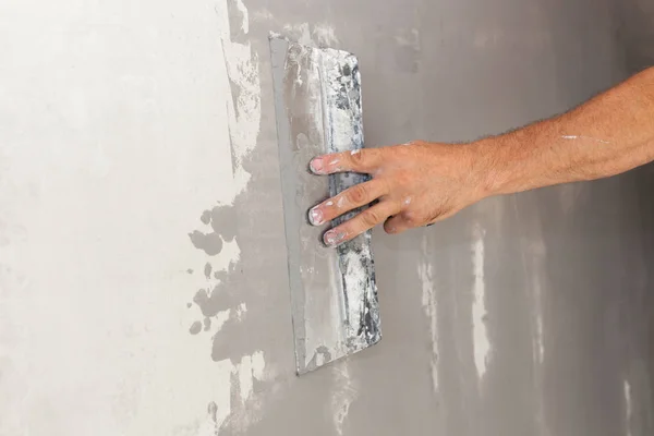 Fechar-se de reparador mão reboco uma parede com faca de vidraceiro ou espátula — Fotografia de Stock