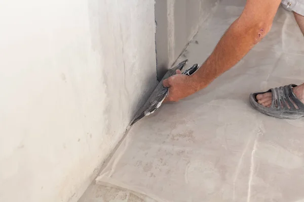 Крупный план ремонтника, оштукатуривающего стену шпаклевкой или лопаткой — стоковое фото