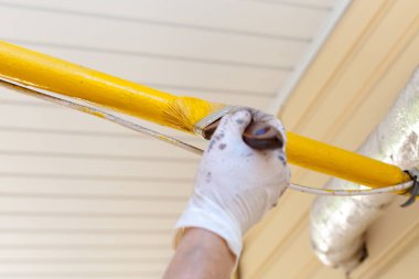 İşçi eldivenleri ile metal tüp Ahşap Saplı bir fırçayla sarı boya renkleri.