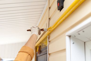 İşçi eldivenleri ile metal gaz boru Ahşap Saplı bir fırçayla sarı boya renkleri.