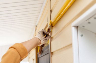 İşçi eldivenleri ile metal gaz boru Ahşap Saplı bir fırçayla sarı boya renkleri.