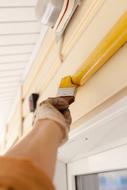 İşçi eldivenleri ile metal gaz boru Ahşap Saplı bir fırçayla sarı boya renkleri.