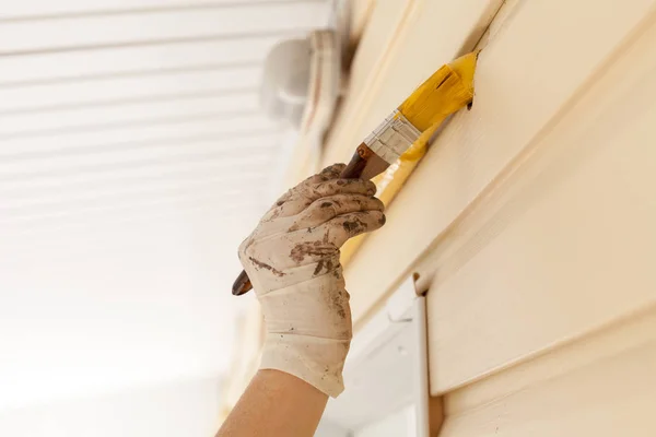 Arbeiter mit Handschuhen färben das Metallgasrohr mit gelber Farbe mit einem Pinsel mit Holzgriff ein. — Stockfoto