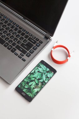 Dizüstü bilgisayar ve smartphone beyaz masa üzerinde şarj çalışma alanı