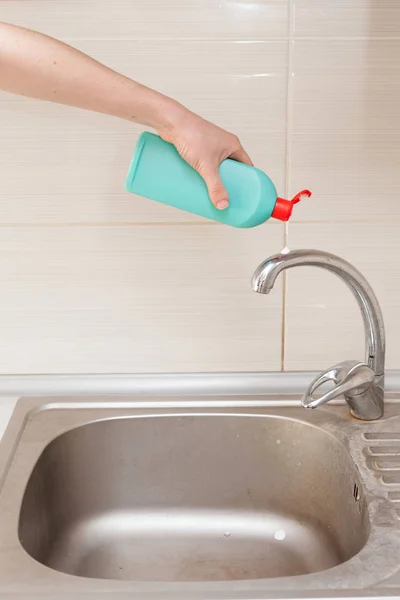 Manos de mujer con botella de detergente de limpieza para fregadero de metal en cocina —  Fotos de Stock