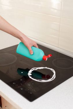 Woman hands with bottle of cleaning detergent for metal sink in kitchen clipart