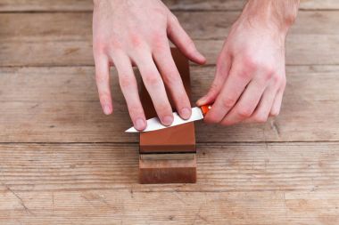 Whetstone bir ahşap zemin üzerine bıçakla keskinleştirme. Üstten Görünüm.